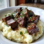 Close-up of juicy Garlic Butter Steak Bites Mash topped with fresh parsley in a white bowl.