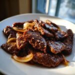 Close-up of glossy, marinated beef slices of Bulgogi mixed with caramelized onions and sprinkled with sesame seeds.