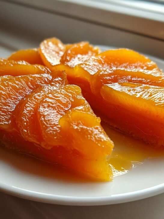 Close-up of thick, glossy slices of homemade Peach Pie Filling arranged on a white plate.