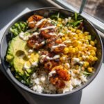 Close-up of a Grilled Shrimp Bowl With Avocado Corn Salsa, featuring grilled shrimp over rice, avocado, and corn.