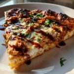 Close-up of a slice of Grilled Summer Bbq Chicken Pizza topped with melted cheese and BBQ sauce.