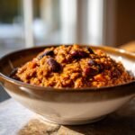 Close-up of a bowl filled with thick, orange Hearty Pumpkin Chili Recipe, topped with dark red kidney beans.