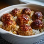 Close-up of glazed meatballs nestled in fluffy rice in a white baking dish, showcasing the Honey Garlic Meatball Rice Bake.