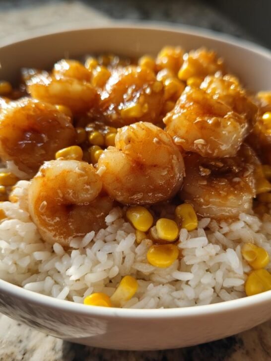Close-up of a Honey Garlic Shrimp And Corn Rice Bowl featuring glazed shrimp over white rice and corn kernels.
