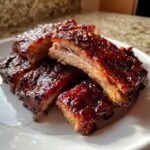 Close-up of tender Honey Jalapeno Party Ribs, heavily glazed with a sticky, dark red sauce.
