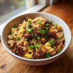 A close-up of a white bowl filled with Instant Pot Chicken Fried Rice, featuring savory chicken pieces, scrambled egg, and fresh green onions.
