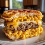 A decadent Macaroni And Cheese Waffle Cheeseburger featuring a beef patty smothered in melted cheese and macaroni.