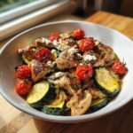 Close-up of Mediterranean Chicken Zucchini Bake with roasted tomatoes and feta cheese in a white bowl.