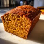 Close-up of a freshly baked, deeply orange Pumpkin Bread Recipe loaf with a moist, textured crumb.
