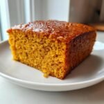 Close-up of a square slice of moist, orange Pumpkin Spice Cake on a white plate.