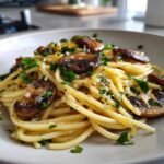 A close-up of perfectly twirled Mushroom And Garlic Spaghetti topped with saut&eacute;ed mushrooms and fresh parsley.