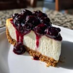 A perfect slice of No Bake Blueberry Cheesecake with a thick graham cracker crust and rich blueberry topping dripping down the side.