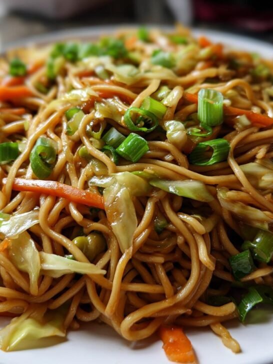 A close-up, appetizing photo of homemade Panda Express Chow Mein noodles mixed with cabbage, carrots, and topped with green onions.