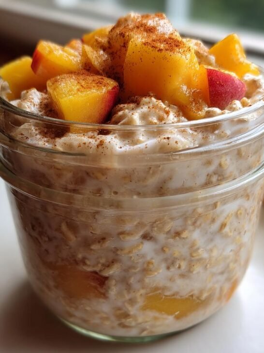 Close-up of Peach Cobbler Overnight Oats Recipe topped with fresh peach chunks and cinnamon.