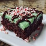A single serving of Peppermint Hot Chocolate Brownies featuring a dark chocolate base, mint green frosting, chocolate drizzle, and crushed candy canes.