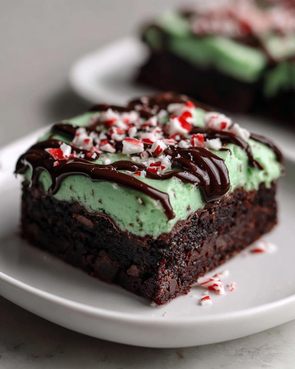 A rich, fudgy Peppermint Hot Chocolate Brownies square topped with mint frosting, chocolate drizzle, and crushed candy canes.