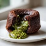 Close-up of a warm chocolate cake with molten pistachio filling oozing out, representing Pistachio Chocolate Lava Cakes.