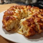 Close-up of freshly baked Pizza Monkey Bread showing a dramatic cheese pull between the pieces.