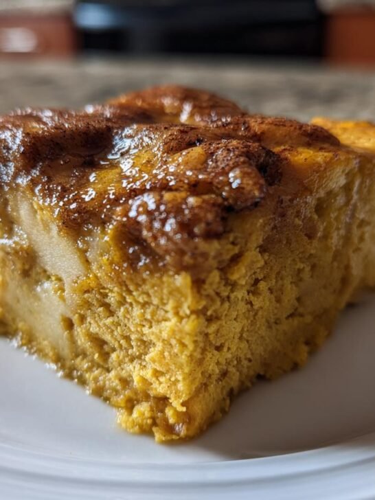A close-up of a rich, moist slice of Pumpkin Bread Pudding Recipe served on a white plate.