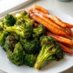 Close-up of perfectly Roasted Broccoli And Carrots served on a white plate, showing caramelized edges.