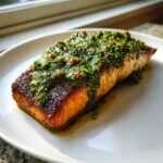 A perfectly cooked fillet of Roasted Salmon With Salsa Verde sitting on a white plate.