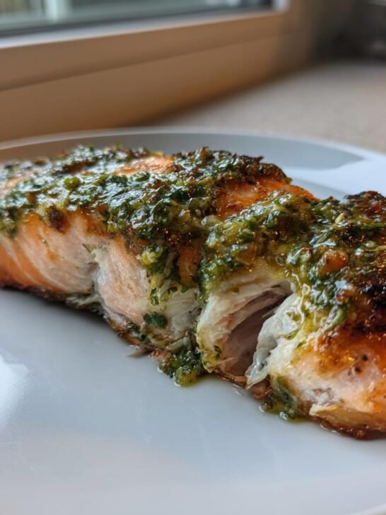 A perfectly cooked fillet of Roasted Salmon With Salsa Verde resting on a white plate.