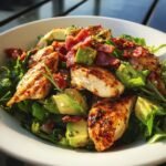 Close-up of Rosemary Chicken Bacon Avocado Salad featuring grilled chicken pieces, avocado chunks, and crispy bacon over greens.