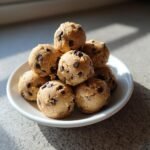 A stack of homemade, safe Cookie Dough Bites loaded with mini chocolate chips, served on a white plate.