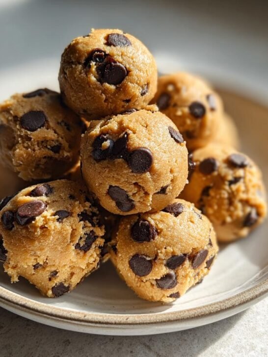 A close-up stack of homemade, safe Cookie Dough Bites loaded with chocolate chips on a small ceramic plate.