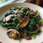 A close-up, tasty shot of freshly prepared Sauteed Mushrooms Spinach served on a light-colored plate.