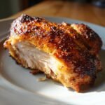 Close-up of perfectly cooked Smoked Garlic Lemon Pepper Chicken showing juicy white meat and crispy, seasoned skin.