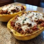 Two halves of Stuffed Spaghetti Squash filled with meat sauce and melted mozzarella cheese.