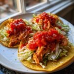 Three fully assembled Salmon Tacos topped with shredded cabbage and bright red salsa.