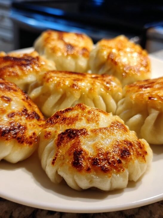 Close-up of several golden-brown, crispy Viral One Pan Baked Dumplings served on a white plate.