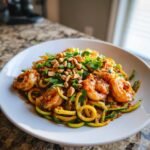A plate of Zucchini Noodle Pad Thai With Shrimp, topped with peanuts and fresh cilantro.