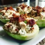 Close-up of three Bacon Ranch Chicken Salad Cucumber Boats filled with creamy chicken salad and topped with crispy bacon bits.