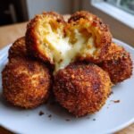 Close-up of golden brown Burrata Stuffed Garlic Cheese Arancini Bombs, one broken open showing melted cheese.