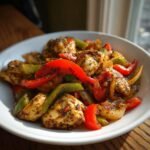 Close-up of seasoned Cajun Chicken With Bell Peppers and onions served in a white bowl.