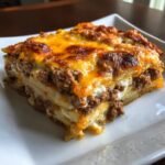 Close-up of a layered slice of Cheesy Ground Beef Potatoes casserole with a browned, melted cheese topping.