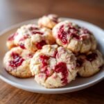 A stack of delicious Christmas Maraschino Cherry Shortbread Cookies with bright red cherry pieces on a white plate.