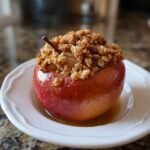 A single baked apple with a rich crumble topping, representing the Cozy Fall Apple Delight.