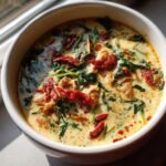 Close-up of a bowl of creamy Marry Me Chicken Soup topped with spinach and sun-dried tomatoes.