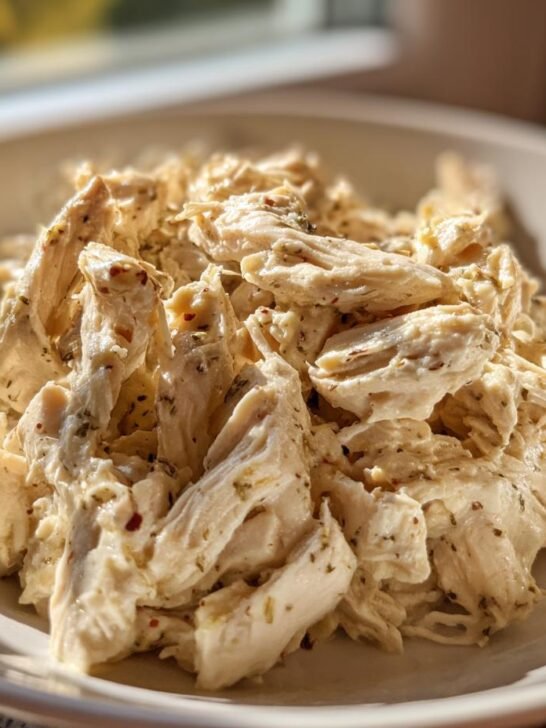 Close-up of shredded chicken coated in a creamy ranch seasoning, ready for the Easy Ranch Chicken Crockpot recipe.
