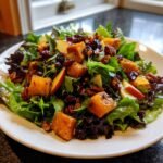 A vibrant plate featuring the Fall Harvest Salad With Butternut Squash And Apple, mixed greens, pecans, and dried cranberries.