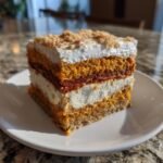 A square slice of Festive Triple Layer Thanksgiving Dessert showing layers of cake, cream, and topping.