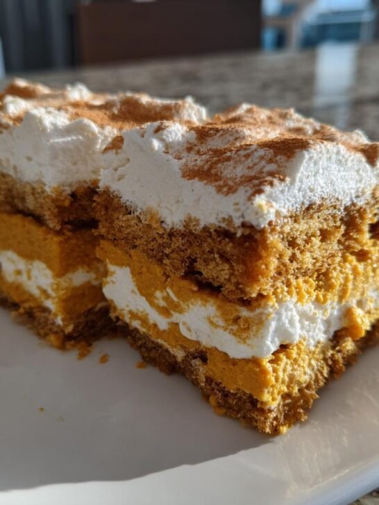 Close-up of two slices of Festive Triple Layer Thanksgiving Dessert showing pumpkin, cream, and cake layers.