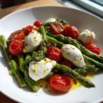 Close-up of a vibrant Fresh Asparagus Tomato Salad With Burrata, featuring green asparagus, roasted tomatoes, and white burrata cheese.