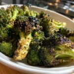 Close-up of perfectly charred Garlic Roasted Vegetarian Broccoli florets served in a white bowl.