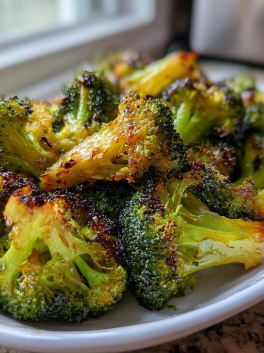 Close-up of perfectly charred Garlic Roasted Vegetarian Broccoli florets served on a white plate.