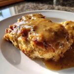 A close-up photo of a perfectly cooked piece of chicken smothered in rich, brown gravy, representing Homemade Chicken And Gravy.